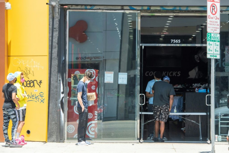 People maintain social distancing while waiting outside a sports clothing store in Los Angeles, California