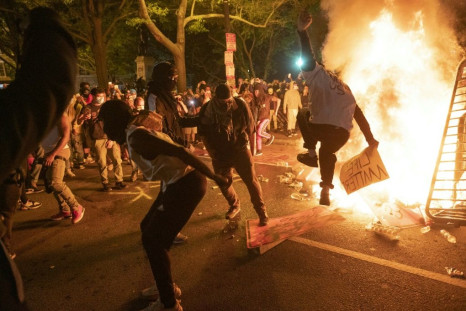 Protesters jump on a street sign near a burning barricade during a demonstration against the death of George Floyd near the White House on May 31, 2020