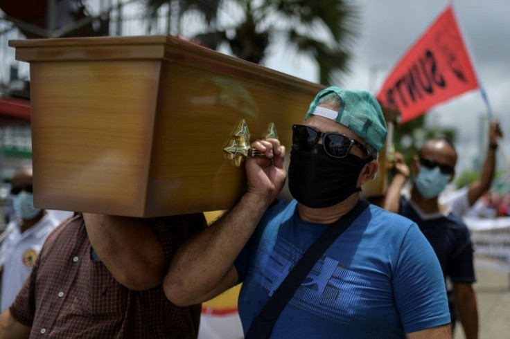 Trade union members in Panama City carry a mock coffin in protest against government measures to reopen the economy, saying it will lead to a spike in coronavirus infections and deaths