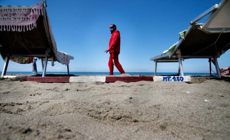 A lifeguard wearing a protective facemask checks the distance between sun beds at Fregene beach near Rome