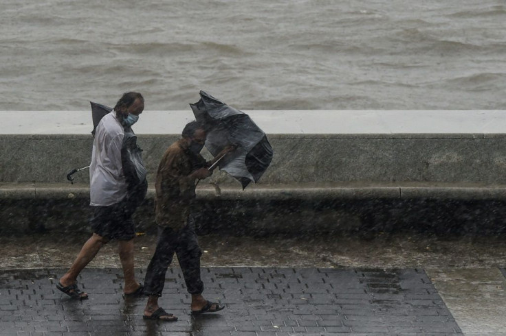 Two men struggle with their umbrellas along Marine Drive in Mumbai as Cyclone Nisarga veered in