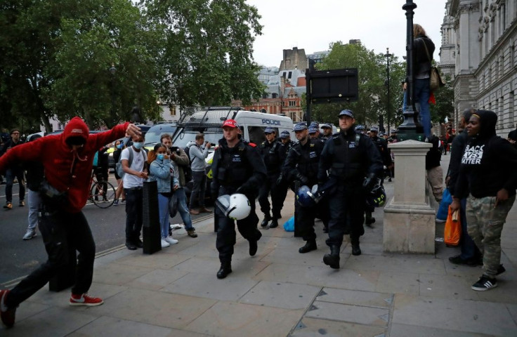 Protestors watch as police officers carrying riot helmets walk along the street near Parliament Square during an anti-racism demonstration in London after George Floyd, an unarmed black man, died in police custody Minneapolis, USA.