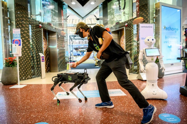A 5G K9 robot distributes hand sanitiser to a visitor at a shopping mall in Bangkok