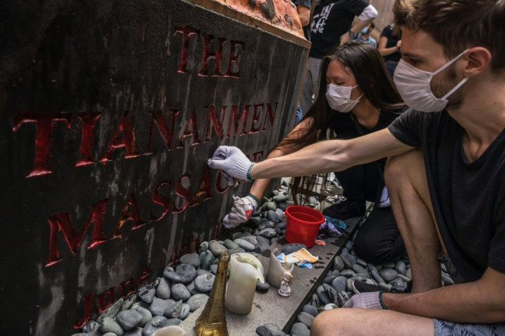 students clean the Pillar of Shame, a statue by Danish artist Jens Galschiot to remember the victims of the 1989 Tiananmen crackdown