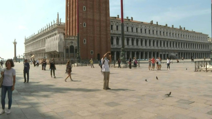People walk around St Mark's Square in Venice, Italy, with some taking pictures of the famous sites as the country reopens to tourists from Europe after a months-long coronavirus lockdown