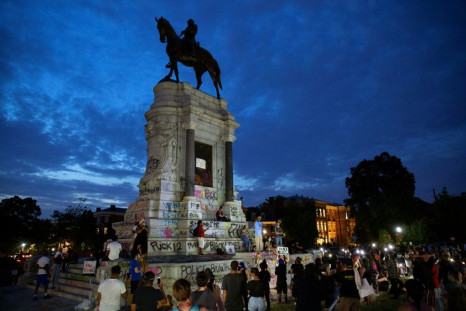 Protestors surround the statue of Confederate general Robert E. Lee in Richmod which the Virginia governor announced would be removed 'as soon as possible'