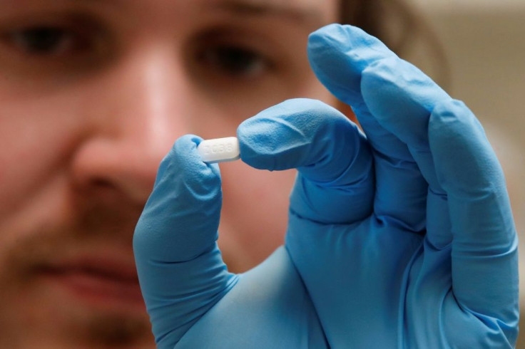 A pharmacy tech holds a tablet of hydroxychloroquine