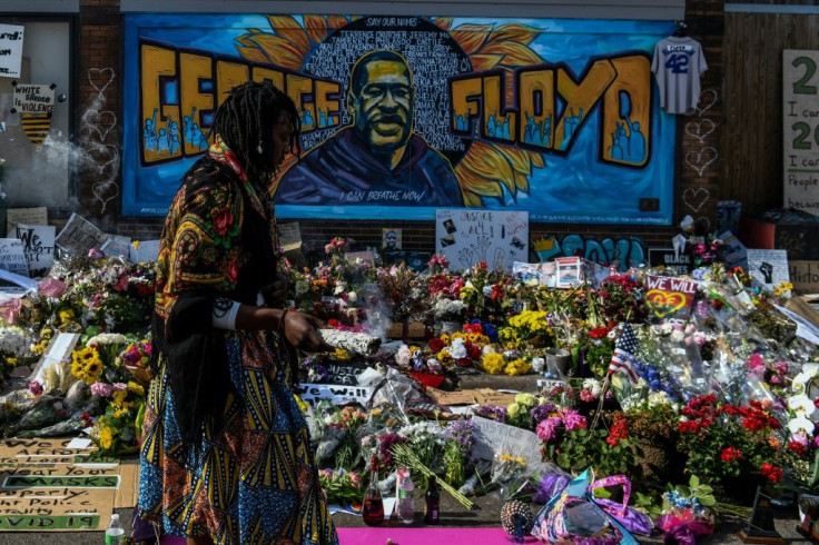 A woman burns sage and offers prayers as she pays her respects at a makeshift memorial in honor of George Floyd, who died while in police custody on May 25