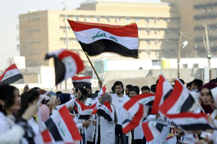 Iraqi medical students wave the national flag as they take part in an anti-government protest in the southern city of Basra in November 2019