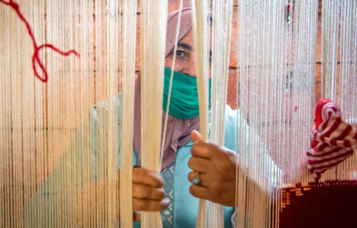 A Moroccan rug weaver peeks from behind carpet thread at a workshop in the city of Sale, north of the capital Rabat