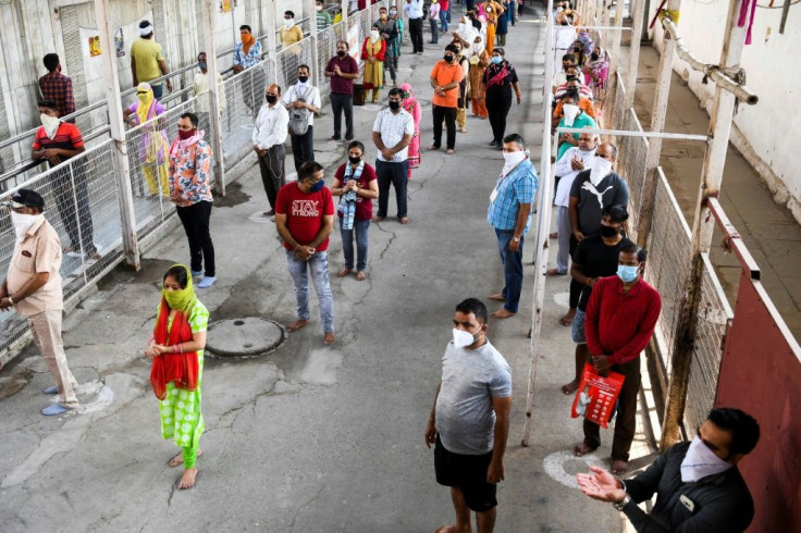 Hindu devotees wait in lines to pray at the Jhandewala temple in New Delhi after certain lockdown restrictions were eased