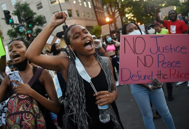 Demonstrators raise their fists and chant as they protest against police brutality and the death of George Floyd across from the White House in Washington