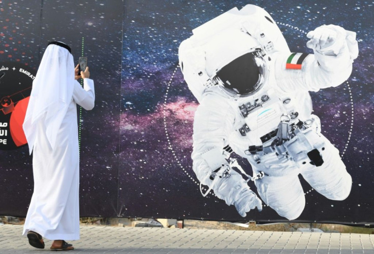 In photo taken on September 25, 2019 a man takes a picture of an illustration depicting an astronaut with the Emirati national flag outside Mohammed Bin Rashid Space Centre in Dubai