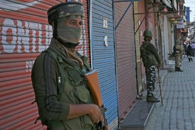 Indian paramilitary troops stand guard in front of closed shops in Srinagar