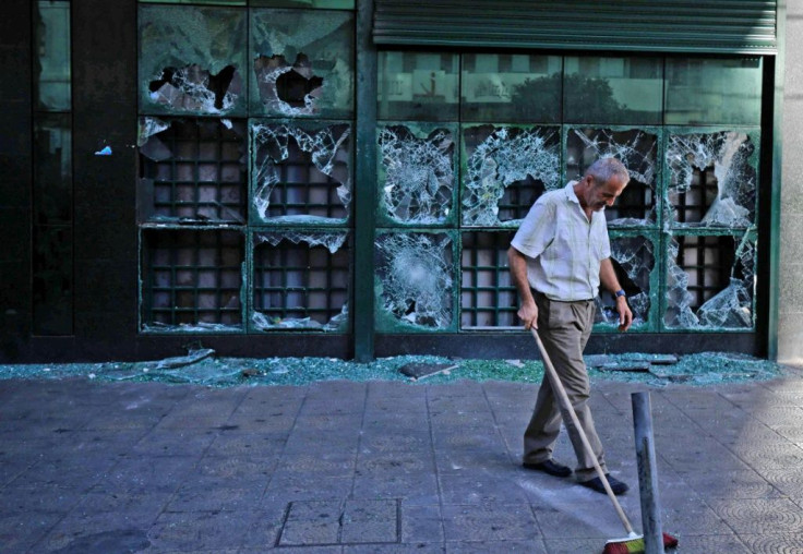 A man cleans up outside a bank that was vandalised by protesters in Lebanon's northern city of Tripoli