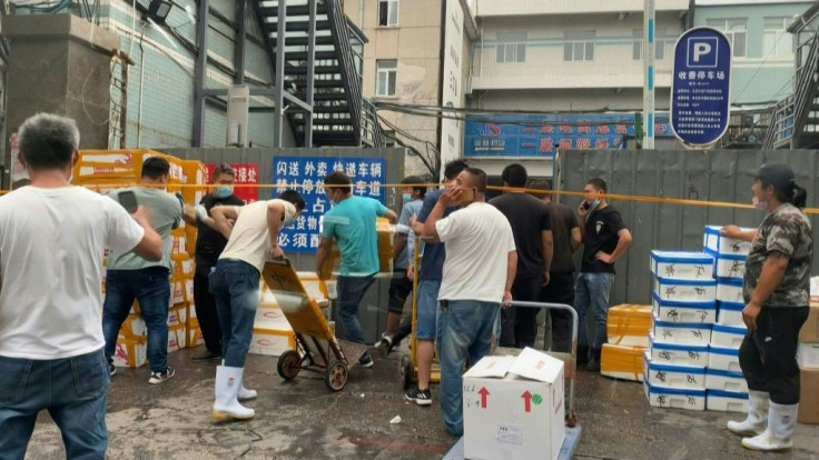 IMAGES People and shop owners move crates and boxes of seafood and goods at Jingshen seafood market, in Beijing's Fengtai district as parts of the city are placed under lockdown.Six new domestic coronavirus cases were reported in the capital Saturday, t