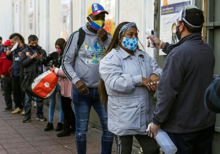 A worker checks the temperature of a customer outside a supermarket in Valparaiso on June 12 as the city went under quarantine