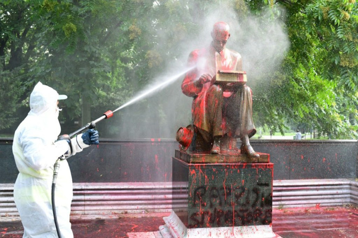 A city worker tries to spray clean the statue of Indro Montanell on Sunday morning after it was vandalised the night before