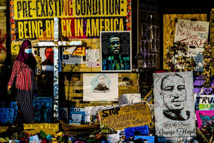 A woman walks past a makeshift memorial to George Floyd near the site where he died in police custody in Minneapolis, Minnesota