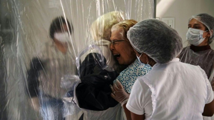 An elderly patient and a visitor at a nursing home in Sao Paulo, Brazil, use a new plastic 'hugging curtain' to embrace while avoiding possible virus contamination
