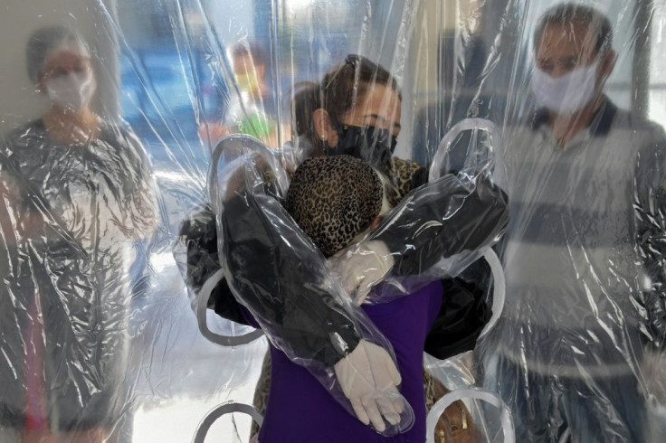 Elisabete Nagata (top) hugs her 76-year-old sister-in-law Luiza Nagata, through a transparent plastic curtain at a senior nursing home in Sao Paulo, Brazil, on June 13, 2020, amid the novel coronavirus (COVID-19) pandemic