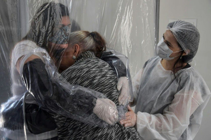 Suzane Valverde (L) hugs her 85-year-old mother Carmelita Valverde, through a transparent plastic curtain at a senior nursing home in Sao Paulo, Brazil, on June 13, 2020, amid the novel coronavirus (COVID-19) pandemic