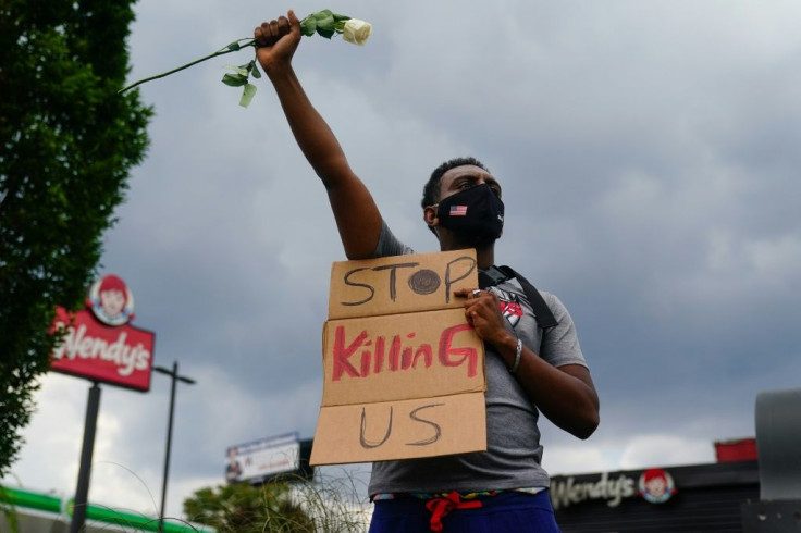 A man holds a sign outside the Wendy's restaurant where Rayshard Brooks was shot dead by police