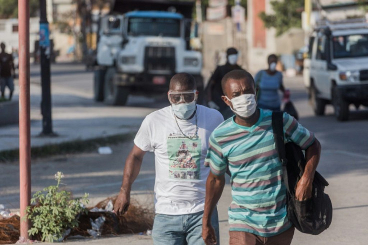 Two men wear masks as they walk in the streets of downtown Port-au-Prince on March 26, 2020. When the novel coronavirus first appeared in Haiti authorities and humanitarian experts panicked, worried about the country's decrepit health system -- but healt