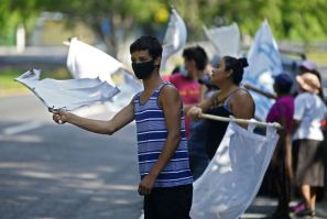 People flutter improvised white flags along a road to show their need for food during a mandatory quarantine imposed by the government against the spread of the new coronavirus in San Pedro Perulapan, El Salvador on June 10, 2020