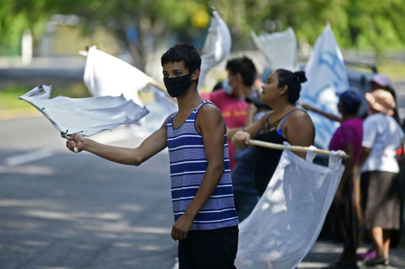 People flutter improvised white flags along a road to show their need for food during a mandatory quarantine imposed by the government against the spread of the new coronavirus in San Pedro Perulapan, El Salvador on June 10, 2020