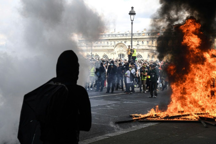 Protesters clad in black set fire to a vehicle and pelted the police with projectiles, chanting "everybody hates the police"