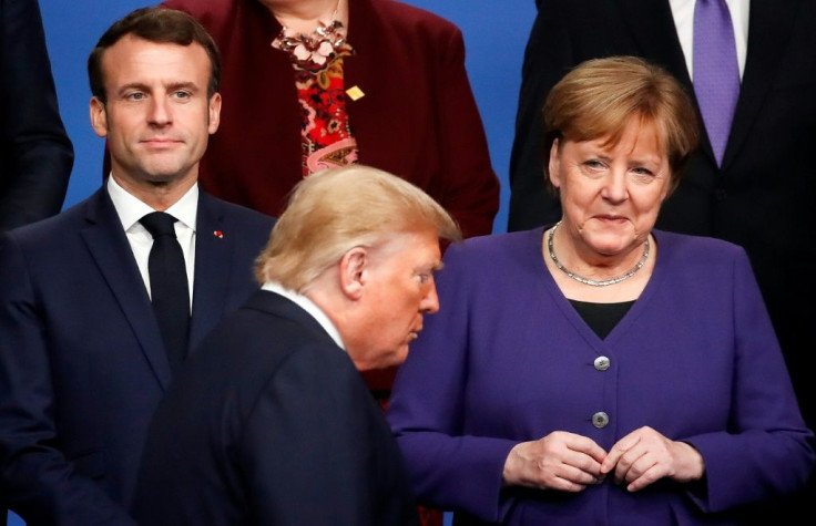 France's President Emmanuel Macron and Germany's Chancellor Angela Merkel look as US President Donald Trump walks past them during a family photo as part of the NATO summit in London in December 2019