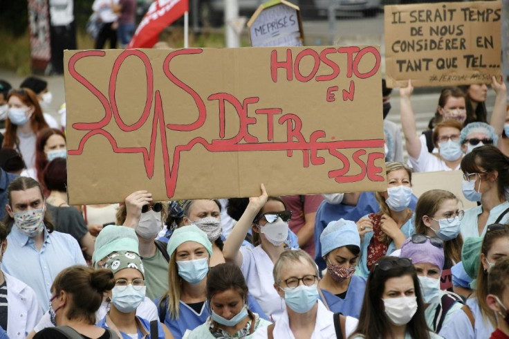 Health workers, one holding a placard reading "SOS Hospitals", take part in a demonstration to demand better working conditions in Strasbourg, eastern France