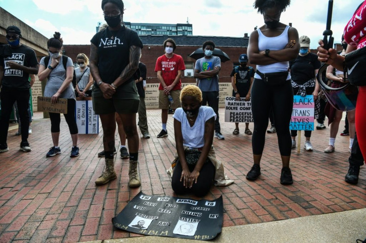 A protester kneels amidst others bowing their heads as they observe eight minutes of silence in honour of Rayshard Brooks at Martin Luther King Jr. National Urban Park n Atlanta