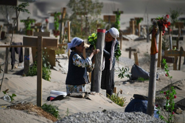 Two women decorate a grave in a Uighur cemetery on the outskirts of Hotan in China's northwest Xinjiang region in May 2019