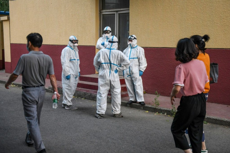 Medical workers in protective equipment take a break at a testing centre for COVID-19 in Beijing this week after a new outbreak whch is also casting fresh doubts over the suspended Chinese Super League football season