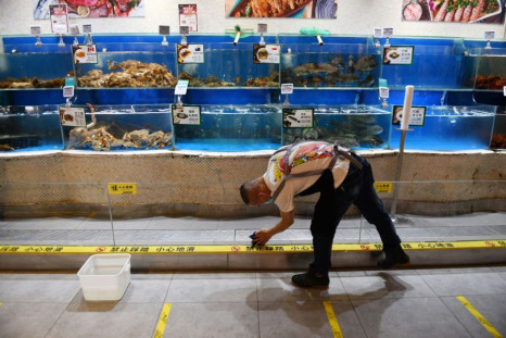 A worker cleans glass in the seafood section of a supermarket in Beijing, where a fresh coronavirus outbreak is keeping customers away