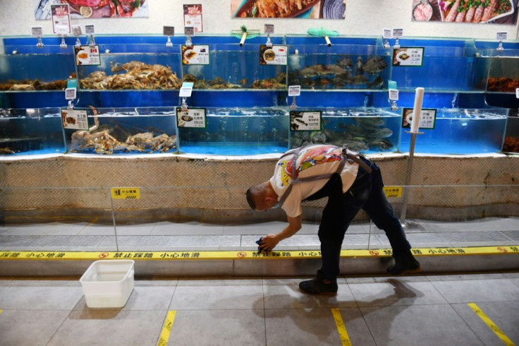 A worker cleans glass in the seafood section of a supermarket in Beijing, where a fresh coronavirus outbreak is keeping customers away