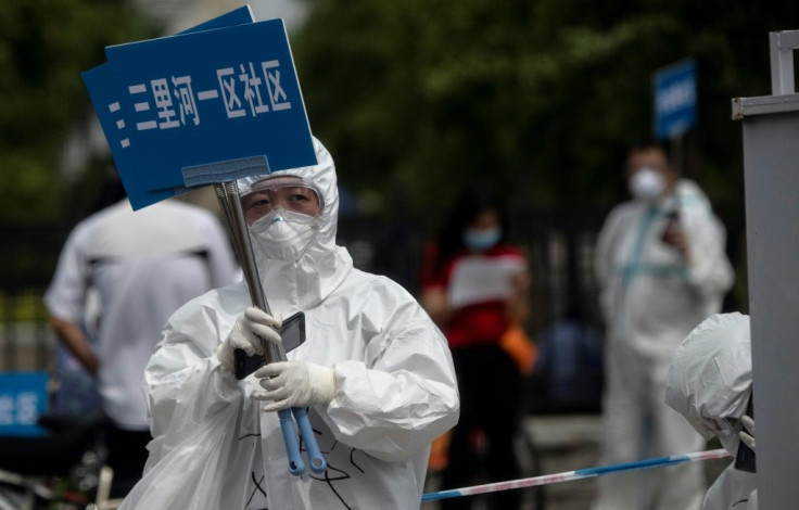 Medical staff in full protective gear carry signs to assist people who live near or have visited Xinfadi market