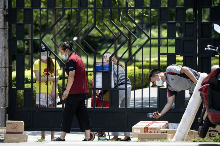 Residents wait behind a gate for items they ordered online at a compound under lockdown
