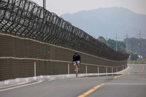 A cyclist rides along the barbed-wire fence of the Demilitarized Zone (DMZ) separating North and South Korea, on the South Korean island of Gyodong on June 18, 2020