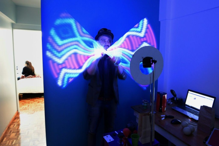 Magician Gustavo Pintos shakes a light-stick as he performs for an online birthday party hundreds of kilometers away from his home in Buenos Aires