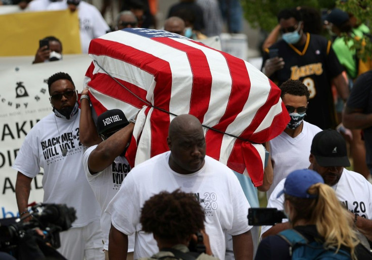 Protesters carry an empty symbolic casket draped with an American flag during a Juneteenth march in Tulsa, Oklahoma