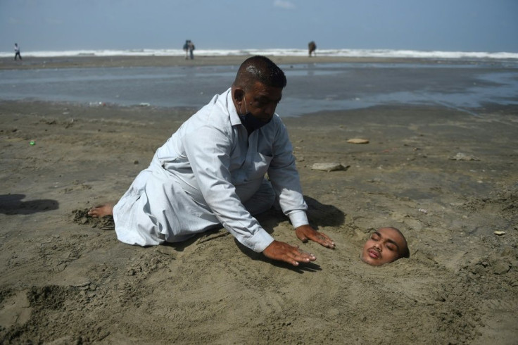 A man buries his paralysed son in sand on a beach in Karachi during the eclipse. Folklore has it if the eclipse passes over them they will be cured