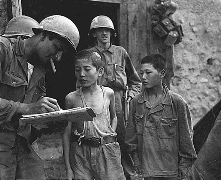 Two boys serving in the North Korean Army are interrogated by a US soldier after they were taken prisoner