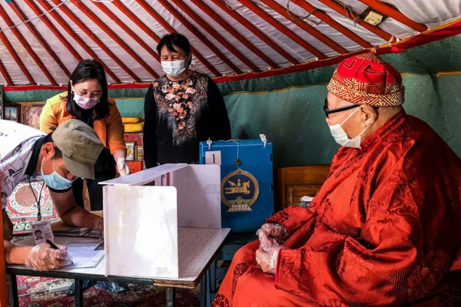 Electoral staff collect the vote of an elderly Mongolian at his home because the man cannot visit a polling station