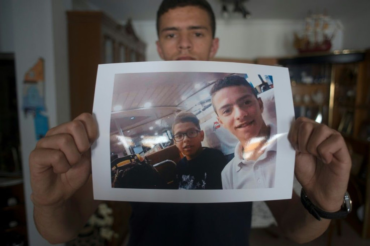 Anass Tahiri, 22, holds a picture of him and his brother, Iliass, who died while being restrained in a juvenile detention centre in Spain
