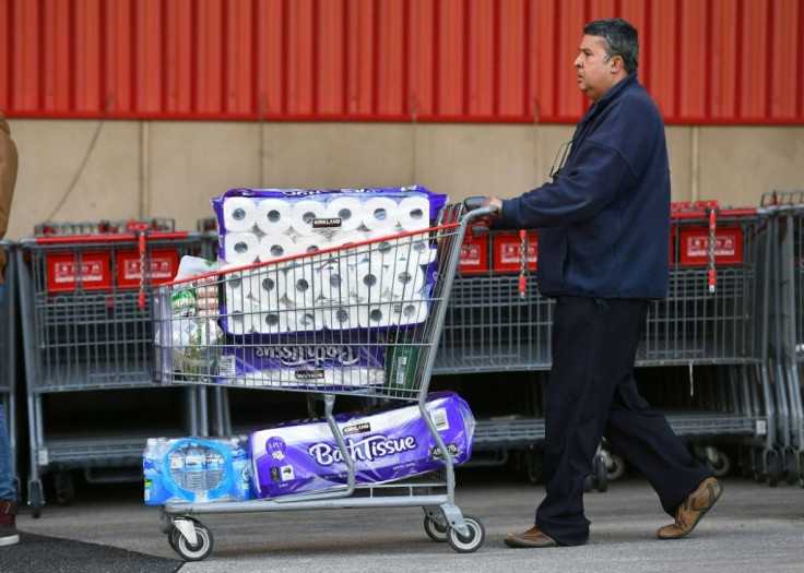 People leave a Costco outlet with a trolley full of toilet paper and cleaning products as fears of a second wave of COVID-19 have sparked a rush on some supermarket items in Melbourne