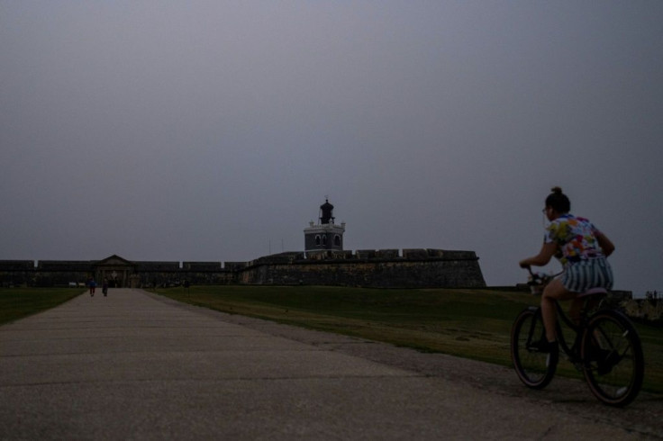 A woman rides her bike in front of El Morro Fort as a vast cloud of Sahara dust blankets the city of San Juan, Puerto Rico on June 22, 2020