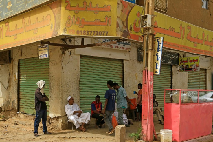 Young people sit outside shuttered pharmacies in the Sudanese capital Khartoum